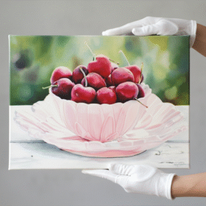 A close-up shot captures a vibrant still life painting featuring a bowl of ripe red cherries, held by white-gloved hands against a neutral background. The painting, presented on a gallery wrap canvas, measures 70x50cm with a 2cm depth, showcasing rich colors and intricate details that highlight the succulent fruit and delicate bowl.
