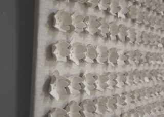 cream clay dimensional abstract lotus flowers arranged in neat rows on European pure linen background. Artwork to be placed in perspect box frame for interior design project for a hotel in Maui.