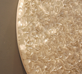 closeup of large round dimensional textured wall art. Thousands of petals created from flexible clay in off-white create this highly textured artwork piece ideal for interior design. Highly decorative art.