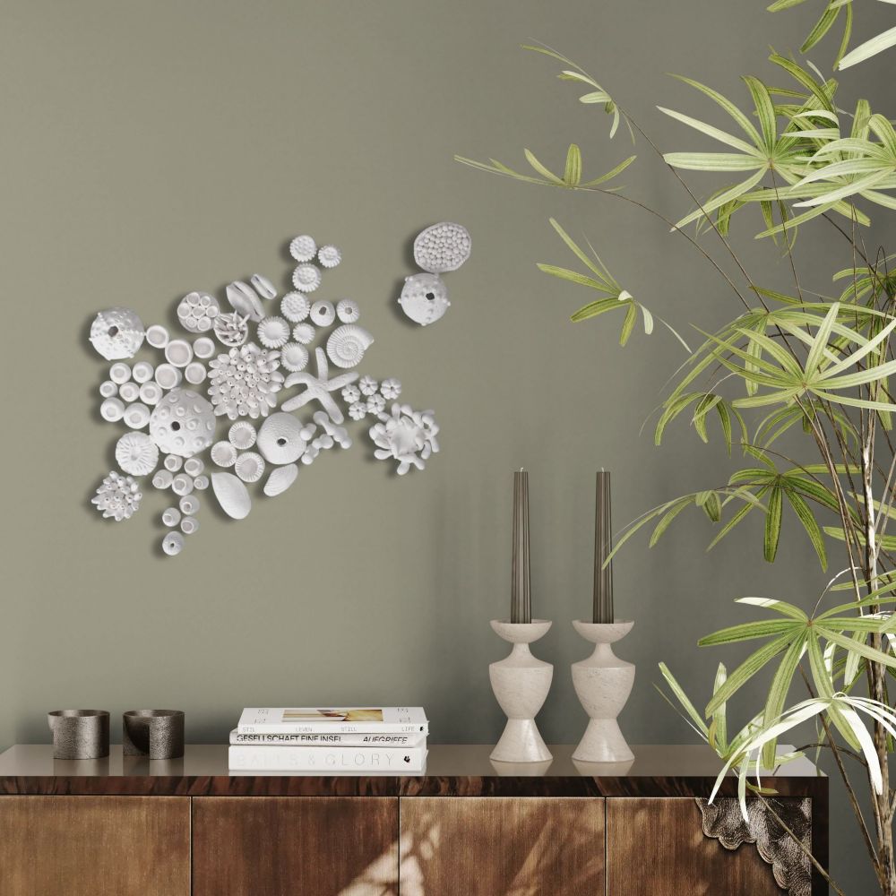 A collection of approximately 60 white, handcrafted clay marine life elements—including various coral forms, sea urchin shells, a starfish, and abstract shell shapes—artfully clustered on a pale blue textured surface, designed for a DIY wall art installation.